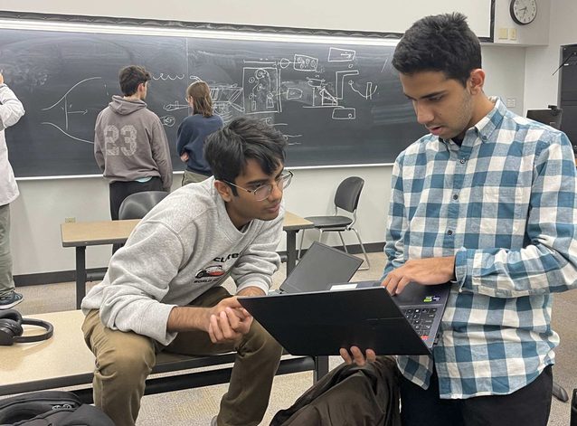 Two members reviewing analysis on a laptop