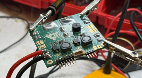 A power distribution board with attached wiring held in place on an electronics workbench